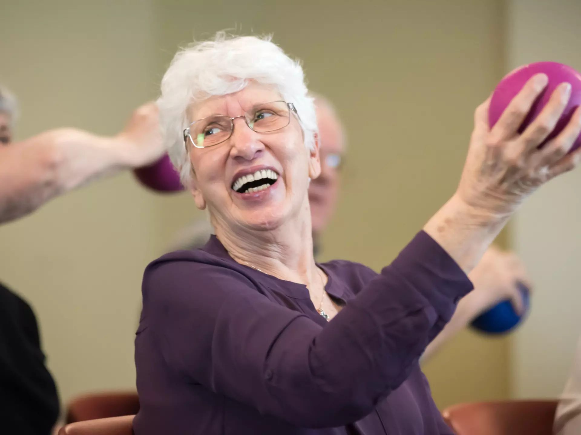 A happy senior is holding an exercise ball.